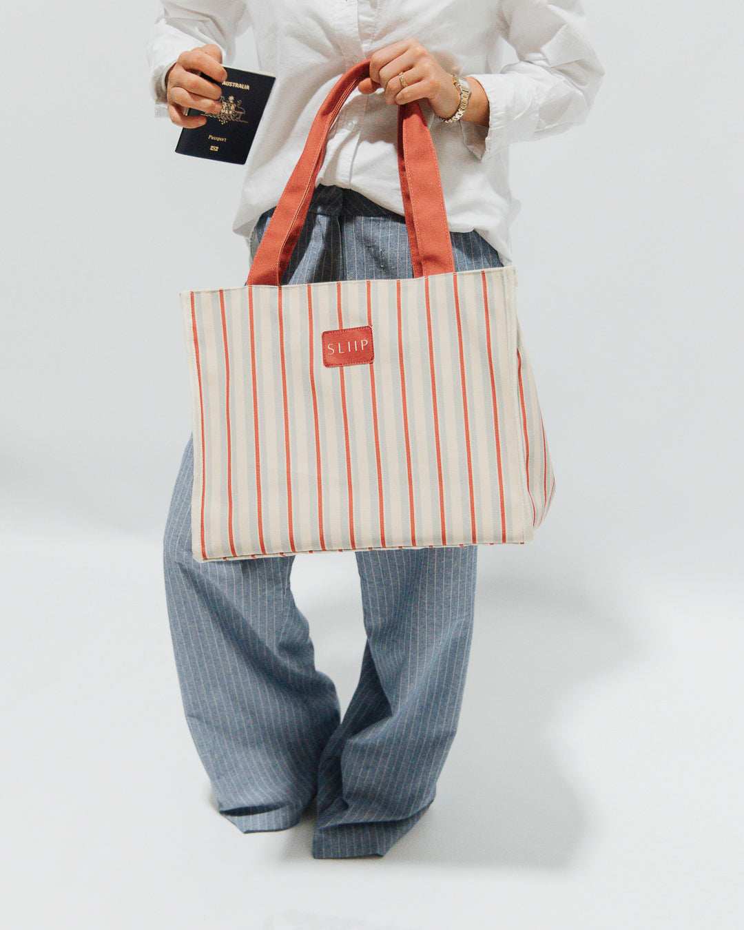 women holding trending striped, red, beige and blue tote bag.