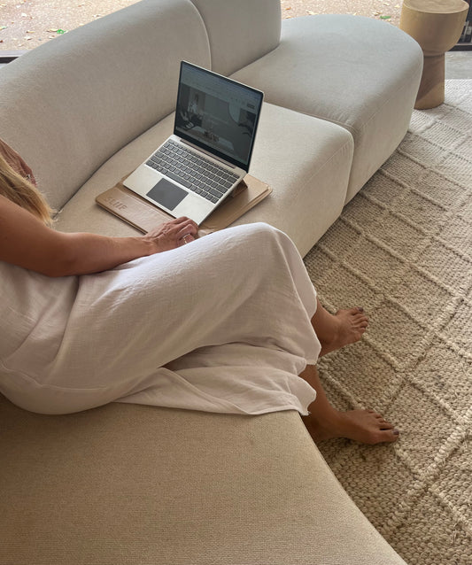 A person sitting on a sofa with a laptop on a stand on the laptop sleeve