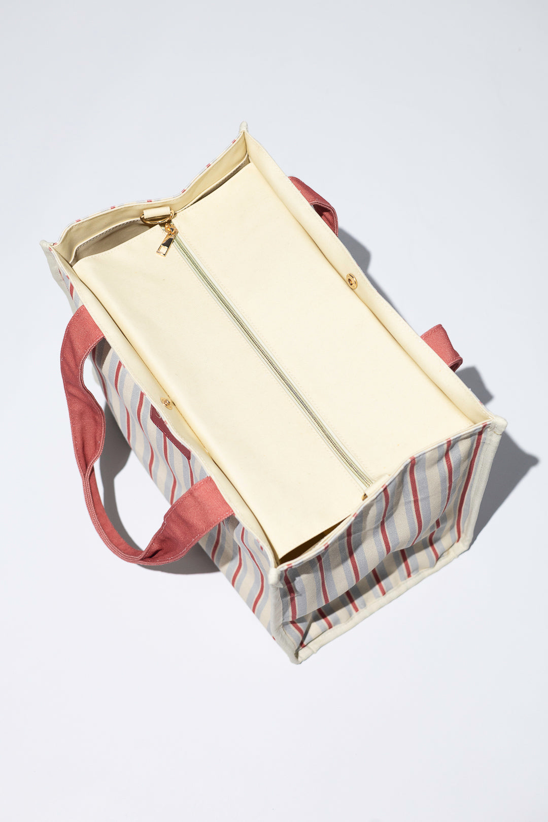 top view of red, blue and beige striped everyday bag, zipper secure top 