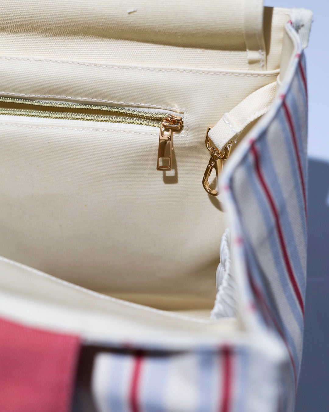close up view of gold hardware and key holder clip on a brown and beige striped tote bag with brown handles 