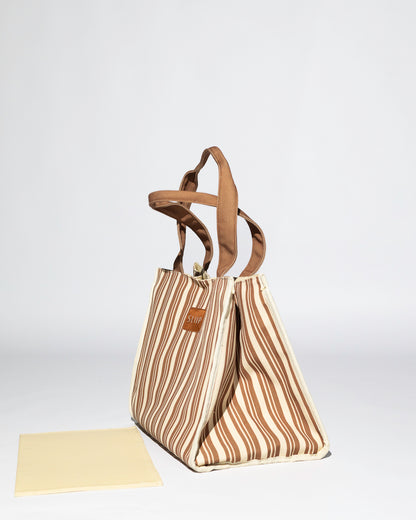 side view of brown and beige striped tote bag with brown handles, showing unstructured mode wth base out